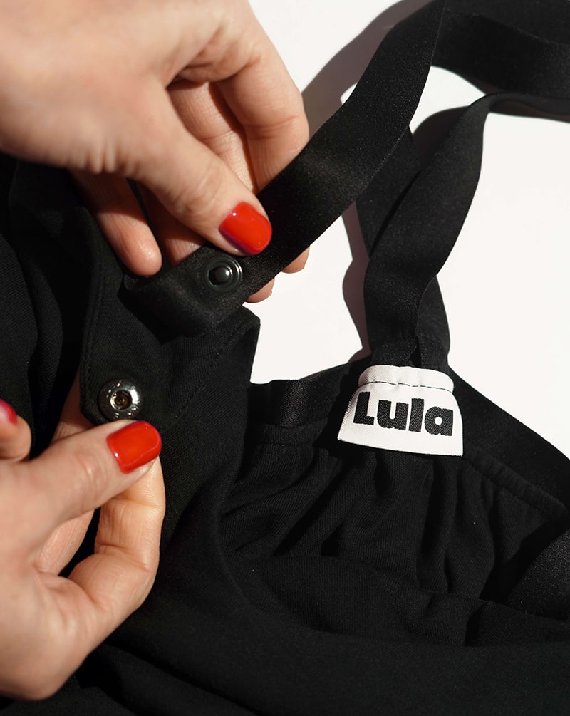 Close-up of the black nursing top's brand label, wide straps, and poppers.