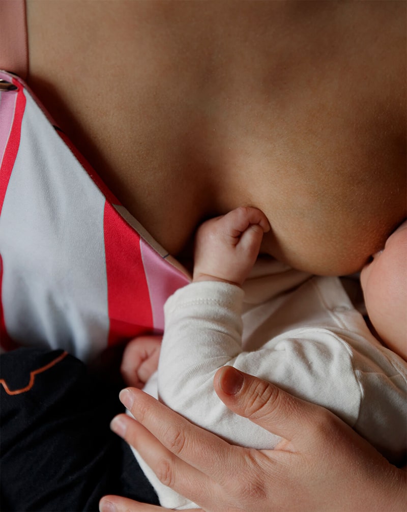 A close-up of a mother breastfeeding her baby in a colorful nursing top, showcasing comfortable clothing.