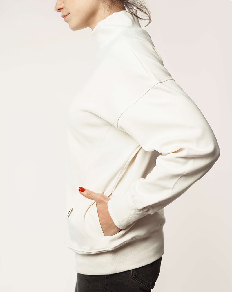 Side view of a white nursing jumper with breastfeeding access and side pockets.