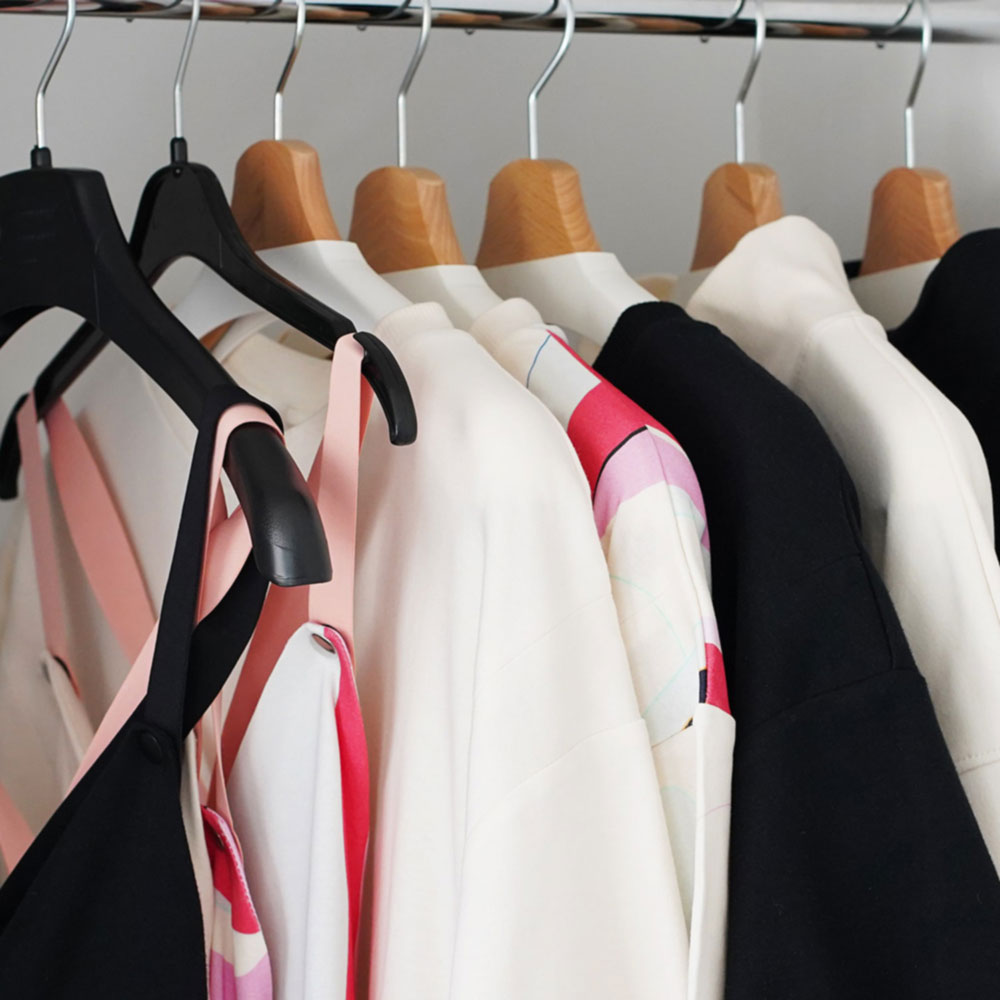 A collection of nursing-friendly clothing on hangers, featuring various colors and styles.