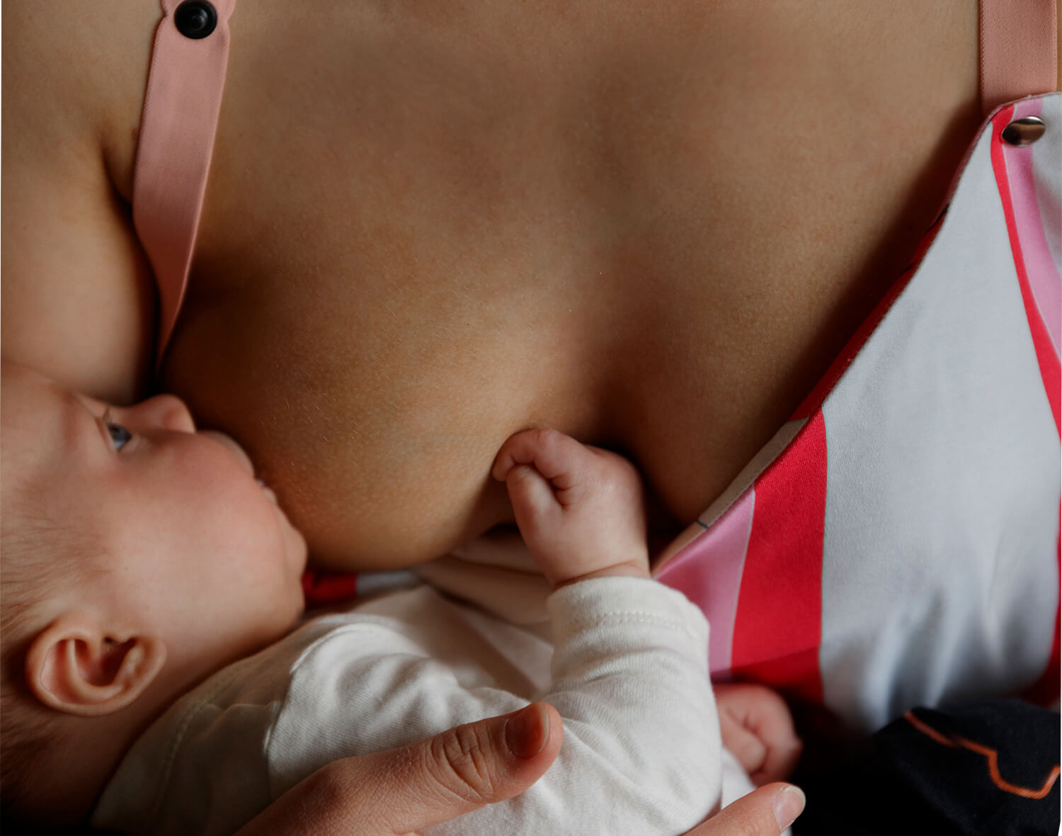 Colorful nursing top worn by mother breastfeeding, showcasing comfortable, nursing-friendly design.