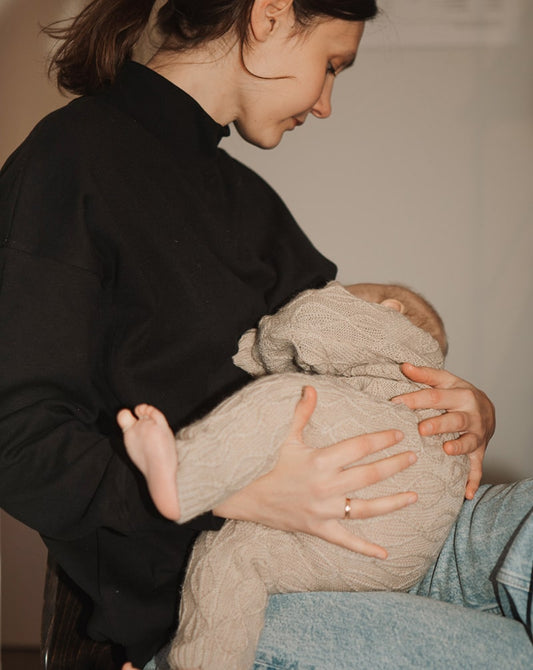 Mother breastfeeding in a black nursing jumper, highlighting nursing-friendly clothing.