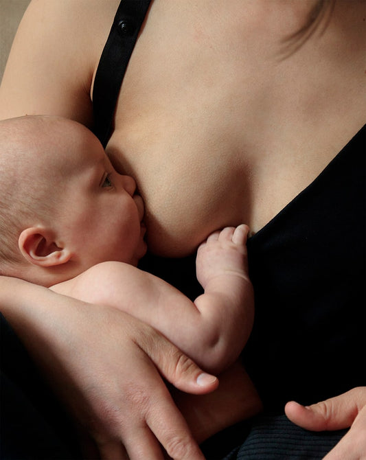 Mother holding her baby in a black nursing top, showcasing a sustainable Nursing outfit.