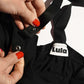 Close-up of the black nursing top's brand label, wide straps, and poppers.
