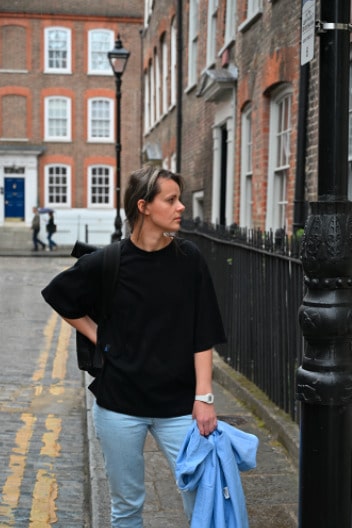 Young mother showcasing a modern nursing t-shirt while walking on the streets of London. Stylish and comfortable breastfeeding clothes for nursing moms on the go.