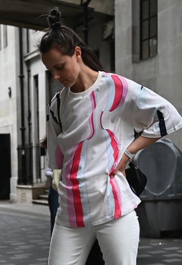 Young mother showcasing a modern nursing t-shirt while walking on the streets of London. Stylish and comfortable breastfeeding clothes for nursing moms on the go.