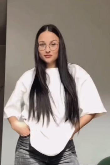 Stylish young mother showcasing a white oversized nursing t-shirt. Modern and comfortable breastfeeding clothes for nursing moms.
