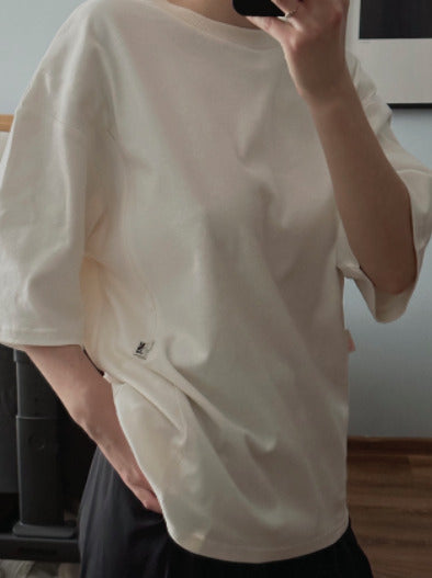 Close-up of a woman taking a mirror selfie wearing an oversized white nursing t-shirt. Modern, stylish, and comfortable breastfeeding clothes for nursing moms.