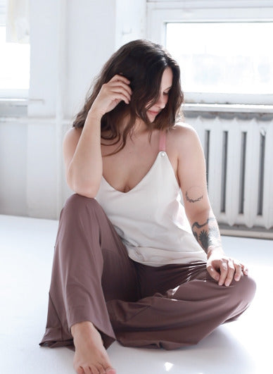Young woman showcasing a white nursing top with pink straps. Stylish, modern, and comfortable breastfeeding clothes for nursing moms.