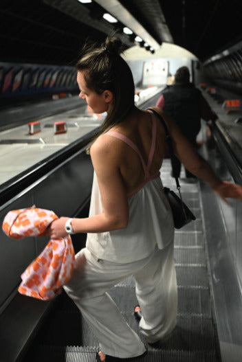 Young mother showcasing a modern nursing top while riding the elevator staircase in metro London. Stylish and comfortable breastfeeding clothes for nursing moms on the go.
