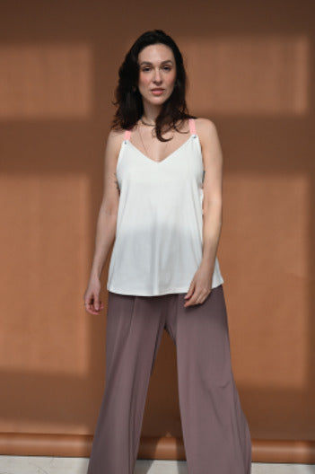 Young woman showcasing a white nursing top with pink straps. Stylish, modern, and comfortable breastfeeding clothes for nursing moms.