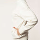 Side view of a white nursing jumper with breastfeeding access and side pockets.
