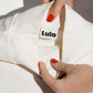 Close-up of the white nursing jumper's collar and the LULA brand label.