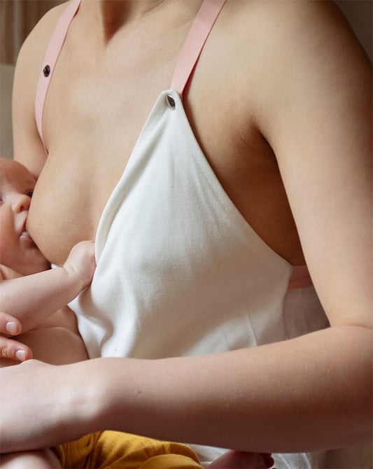 Mother holding her baby in a white nursing top, showcasing a sustainable nursing clothing.