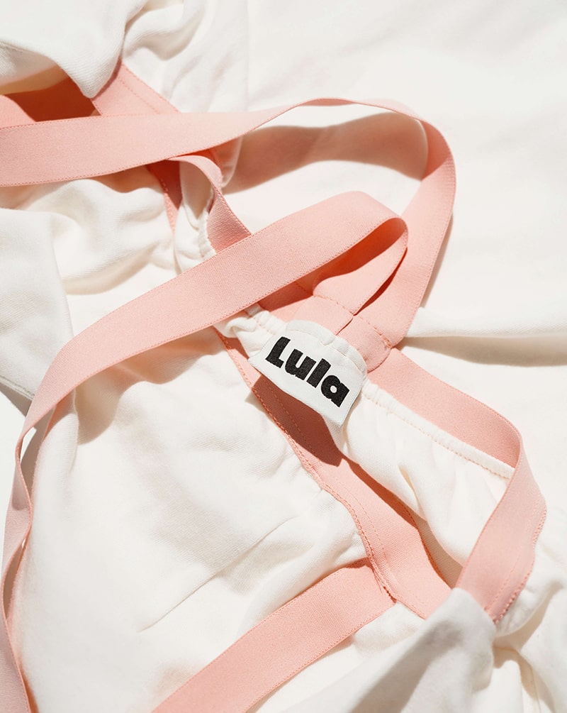 Close-up of the white nursing top's brand label and wide pink straps.