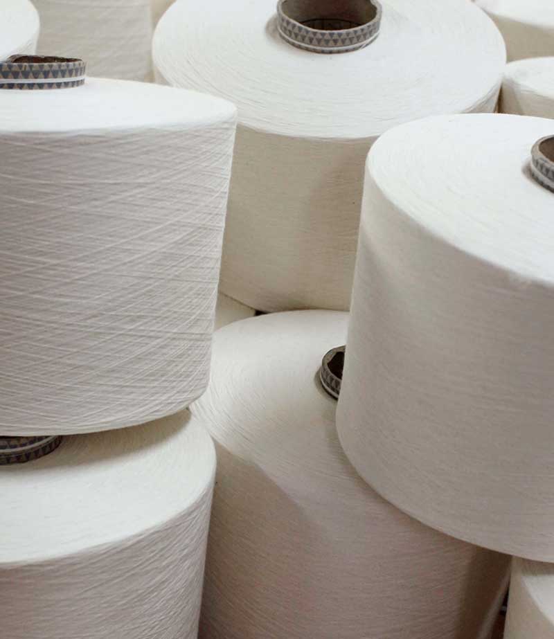 Close-up of white organic cotton thread spools, highlighting sustainable fashion production.