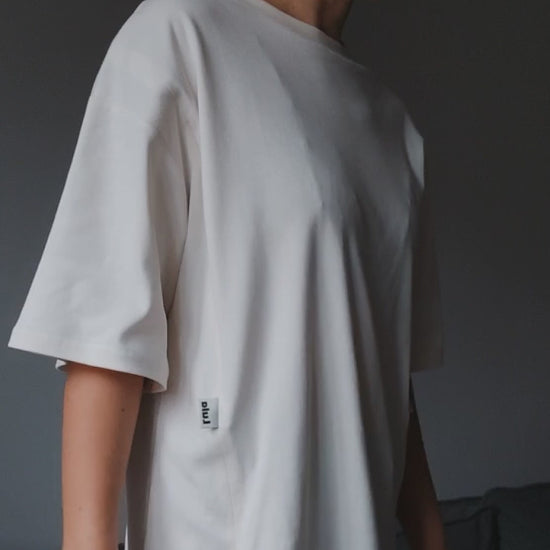 Video of a model demonstrating a white oversized nursing t-shirt with easy breastfeeding access.