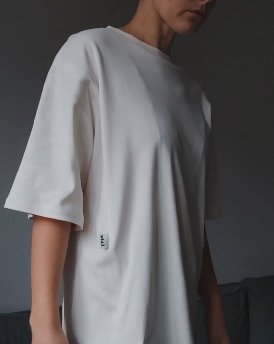 Video of a model demonstrating a white oversized nursing t-shirt with easy breastfeeding access.