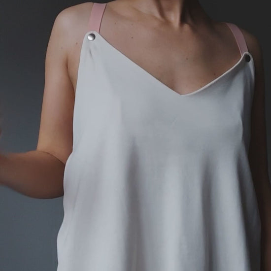 Video of a model demonstrating a white nursing top with snap-button fastening for easy breastfeeding access.