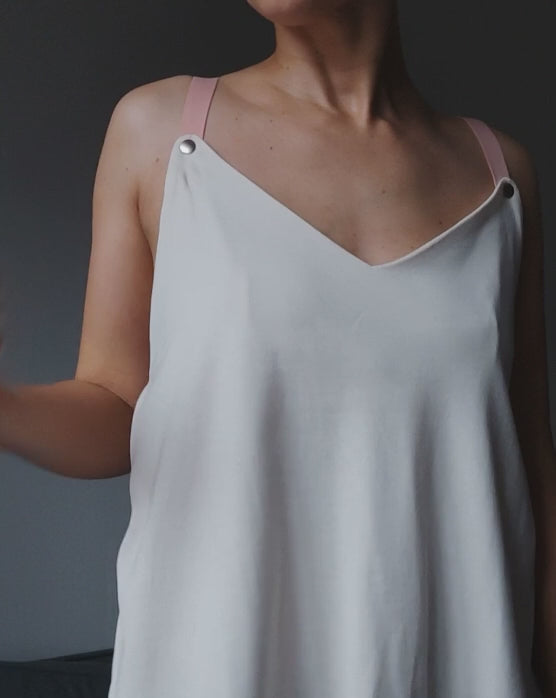 Video of a model demonstrating a white nursing top with snap-button fastening for easy breastfeeding access.